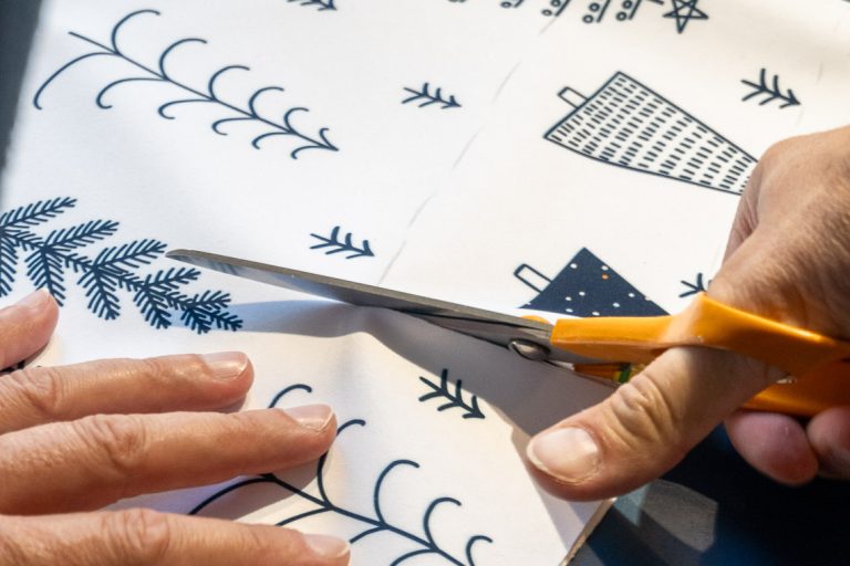 Präzise Zuschnittarbeit für den Softshell-Dackelmantel: Professionelle Verarbeitung des exklusiven Winterdesigns mit festlichen Motiven
